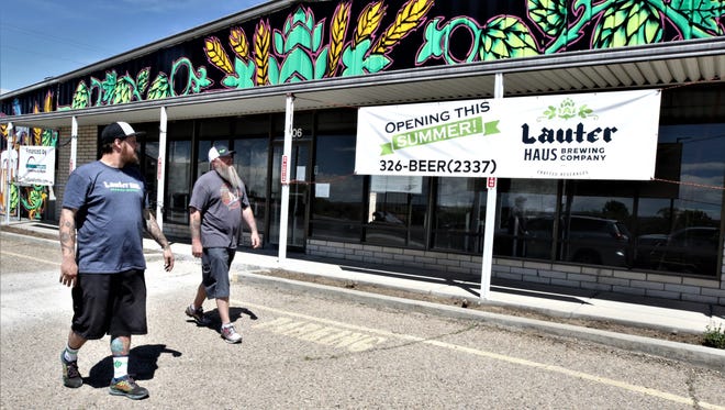 Brandon Beard, left, and Brad Foley examine a sign promoting the planned opening this summer of their Lauter Haus Brewing Company in Farmington.