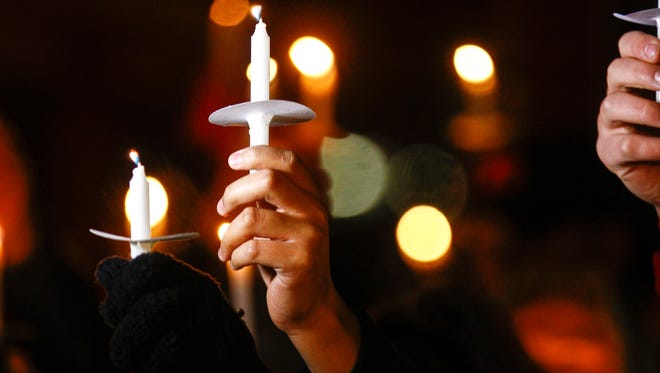 Community members hold their candles Thursday during a vigil for Aztec High School shooting victims at Minium Park in Aztec.