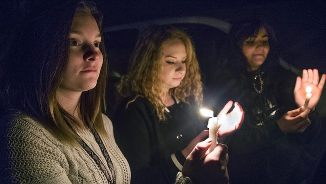 Dallas Baron, 18, left, Nevaeh Jaramillo, 15, and Heaven Hughes, 15, hold candles during a Thursday night vigil for the Aztec High School shooting victims in Minium Park in Aztec.