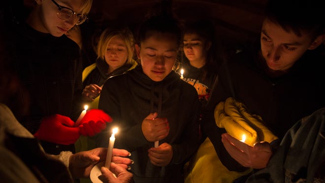 From left, Tyler Shahan, Bianca Martinez, center, and Joshua Carrillo light candles for their friend Casey Jordan, Thursday, Dec. 7, 2017 during a candle light ceremony at Minium Park in Aztec, N.M.