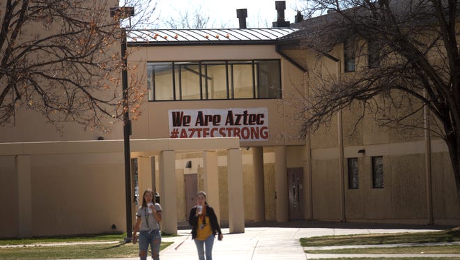 Aztec High School students pass under a banner supporting the school and community on Thursday on the school's campus.