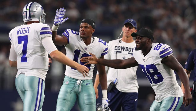 Cooper Rush #7 of the Dallas Cowboys is greeted on the sidelines by Brice Butler #19 of the Dallas Cowboys and Dez Bryant #88 of the Dallas Cowboys after throwing a touchdown pass in the second half of a preseason game at AT&T Stadium on August 19, 2017 in Arlington, Texas.