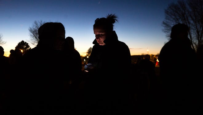 Aztec resident Natali Sandes waits with other community members on Thursday for the start of a candlelight vigil for Aztec High School shooting victims at Minium Park in Aztec.