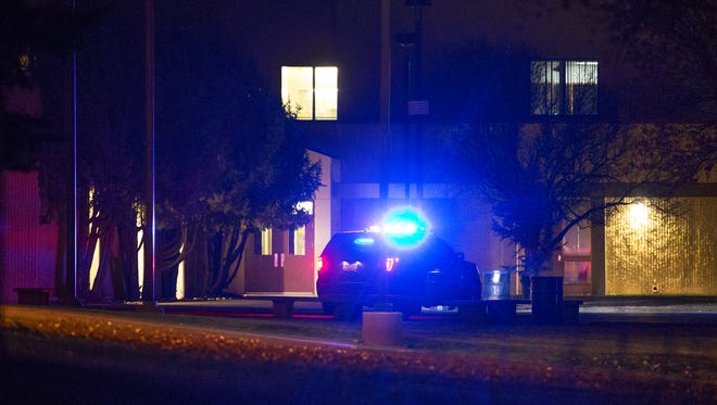 A police car sits outside Aztec High School in Aztec, New Mexico at 10 pm, Thursday, December 7, 2017, after three people were shot to death Thursday morning.