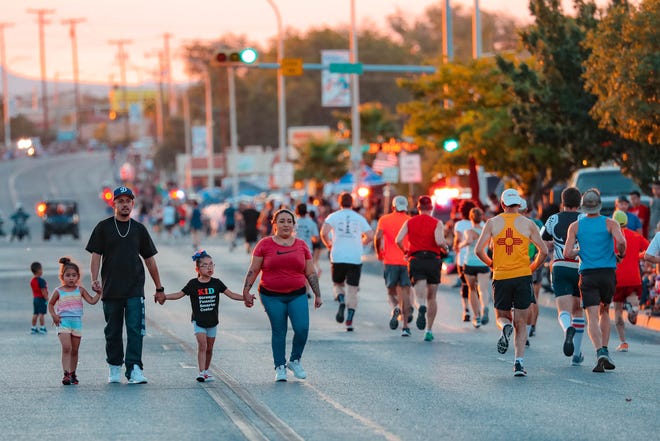 A family walks across the street before the annual Las Cruces Electric Light Parade near Apodaca Park on Wednesday, June 3, 2019.