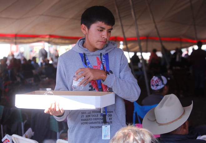 Delaine Loley, a student at Northwest High School, hands out bottled water at Elder Fest during the 108th Northern Navajo Nation Fair on Oct. 3 in Shiprock.