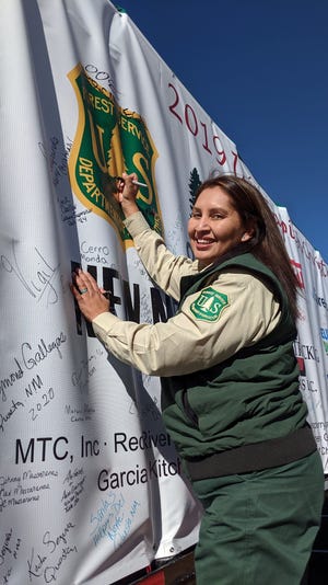 Erica Enjady adds her name to the protective cover of the Capitol Christmas tree.