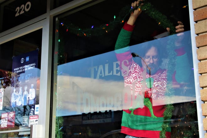 Steve Clark of Tales of Tomorrow comic book store in Farmington hangs holiday lighting on Nov. 30, 2019, Small Business Saturday.
