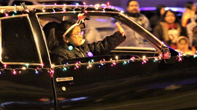 A child waves out of the car of a member of the Northern New Mexico Street Rodders at Farmington's annual Christmas Parade in Farmington on Dec. 5, 2019.