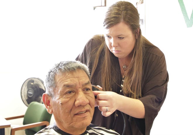 From right, AmeriCorps member Jennifer Arthur cuts San Juan Chapter President and Army veteran Sam Bee's hair on Dec. 6 at the San Juan Chapter house in Lower Fruitland.