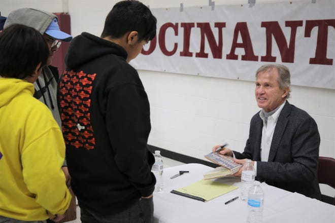 Author Rodney Barker signs a copy of his book "The Broken Circle" for a Rocinante High School student on Jan. 10, 2020, after an assembly at the school in Farmington.