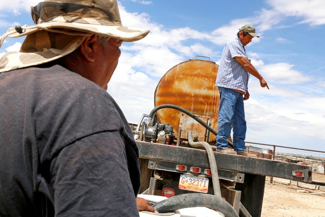 At left, Richard Root and Melvin Jones, both equipment operators for the Shiprock Chapter house, deliver water to a residence in Shiprock for livestock usage on Aug. 11, 2015.