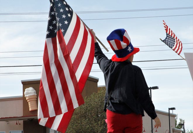 A protester waves an American flag, Thursday, May 14, 2020, in front of the Animas Valley Mall in Farmington.