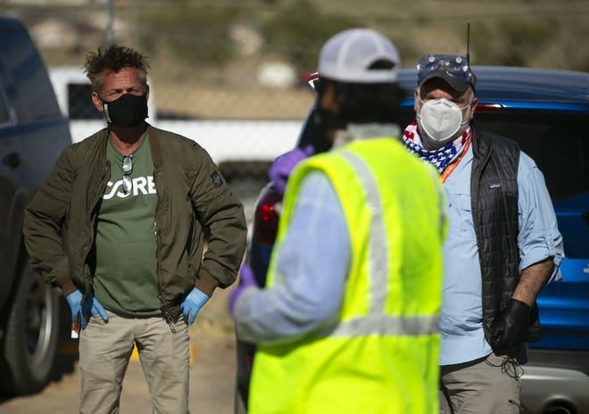 Actor Sean Penn (left) and celebrity chef Jose Andres (right) listen as Navajo Nation President Jonathan Nez speaks at a food distribution point before the start of a weekend-long curfew in Coyote Canyon, New Mexico, on the Navajo Nation on May 15, 2020.