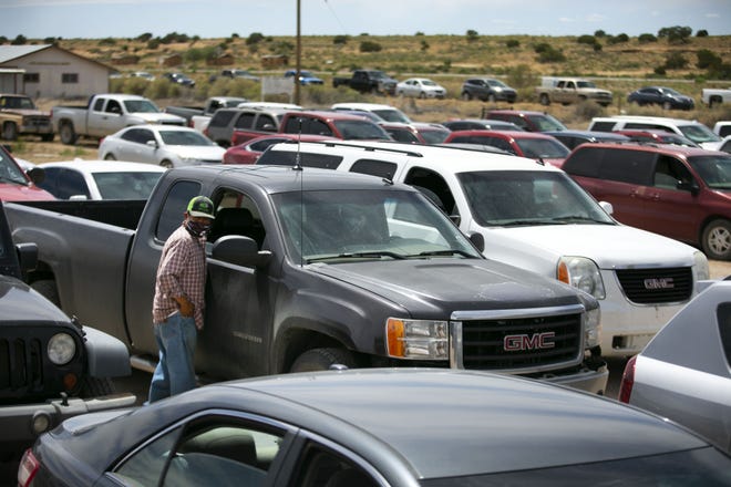 Cornel Iyua talks to a fellow community member while people wait in their vehicles to receive food at a food distribution point before the start of a weekend-long curfew in Coyote Canyon, New Mexico, on the Navajo Nation on May 15, 2020.