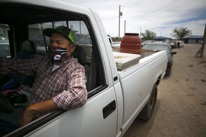 Cornel Iyua waits in his vehicle to receive food at a food distribution point before the start of a weekend-long curfew in Coyote Canyon, New Mexico, on the Navajo Nation, on May 15, 2020.