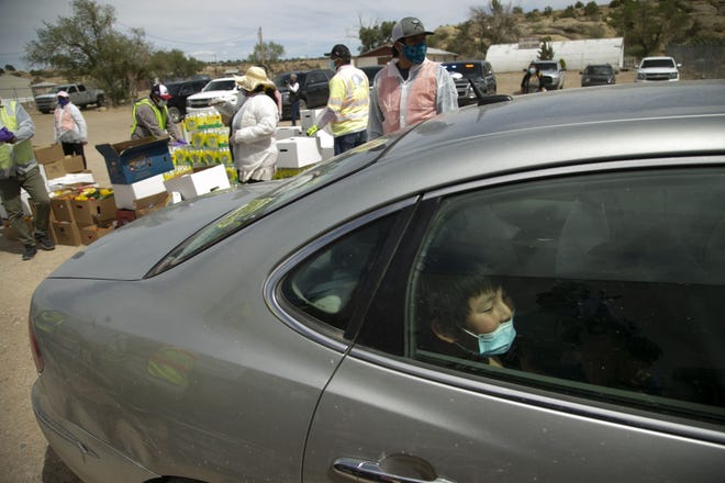 A young boy sits in the back of a vehicle as food is distributed to community members in their vehicles at a food distribution point before the start of a weekend-long curfew in Coyote Canyon, New Mexico, on the Navajo Nation on May 15, 2020.