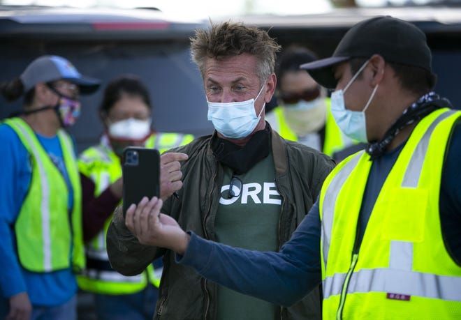Actor Sean Penn records a video on a community member's phone at a food distribution point before the start of a weekend-long curfew in Coyote Canyon, New Mexico, on the Navajo Nation on May 15, 2020.