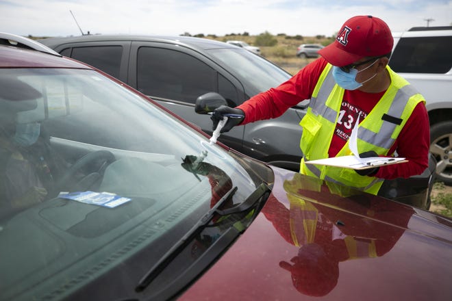 Alberto Peshlakai of the Navajo Nation Office of the President and Vice President, marks vehicles to receive food before the start of a weekend-long curfew in Coyote Canyon, New Mexico, on the Navajo Nation, on May 15, 2020.