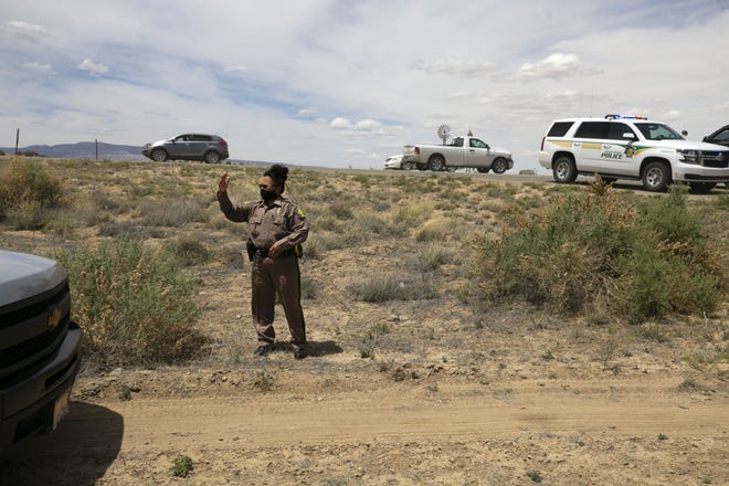 Officer Netty Etsitty of the Navajo Tribal Police directs traffic at a food distribution point before the start of a weekend long curfew, in Coyote Canyon, New Mexico, on the Navajo Nation, on May 15, 2020.