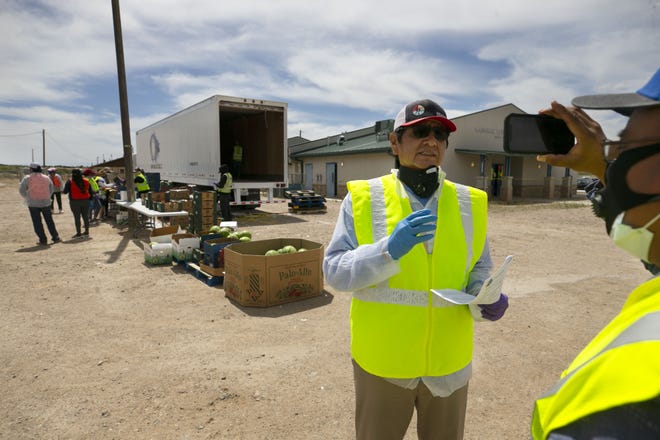 Jared Touchin (right), communications director of the Navajo Nation Office of the President and Vice President, records a video of Navajo Nation President Jonathan Nez (center) as food is distributed to community members at a food distribution point before the start of a weekend-long curfew in Coyote Canyon, New Mexico, on the Navajo Nation, on May 15, 2020.