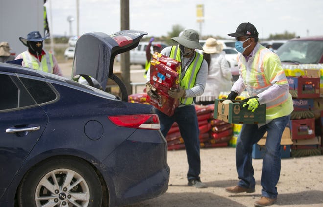 Volunteers, staff member of the Coyote Canyon chapter and the Navajo Nation Office of the President and Vice President, place fresh food, water and dog food into community members' vehicles at a food distribution point before the start of a weekend-long curfew in Coyote Canyon, New Mexico, on the Navajo Nation on May 15, 2020.