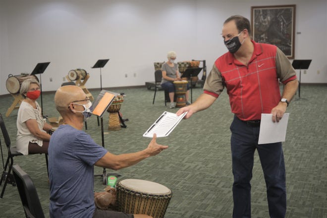 San Juan College music professor Teun Fetz grins as he hands sheet music to student Charlie Higby on Aug. 24, 2020, during an African drumming class on the college campus in Farmington.
