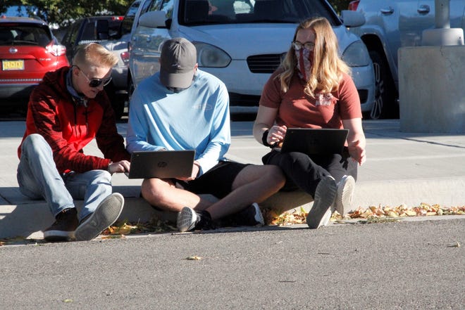 A trio of Bloomfield High School students work on classwork, Monday, Oct. 12, 2020, while protesting the state public health orders that prevent them from attending class in person or participating in sports. The group was part of a protest at the high school.