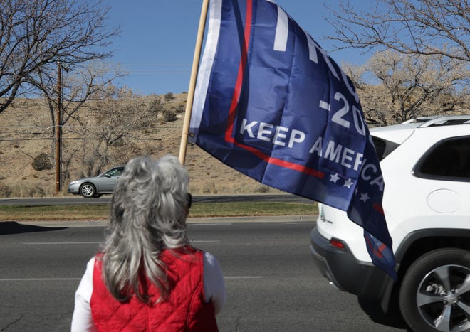 A woman holds a Trump flag, Saturday, Nov. 21, 2020, while protesting public health orders.