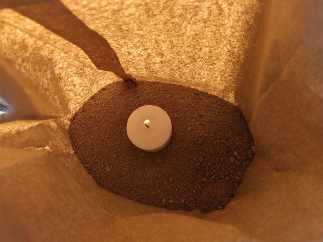 A candle burns, Saturday, Dec. 5, 2020, inside a luminaria bag.