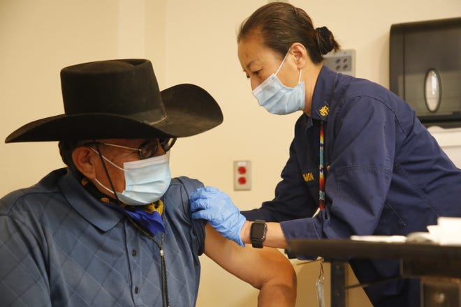 At right, U.S. Public Health Service Commissioned Corps Cmdr. Hosun Persimmon finishes rolling up Navajo Nation Council Delegate Eugene Tso's sleeve before administering the Pfizer-BioNTech COVID-19 vaccine on Dec. 31, 2020 at Gallup Indian Medical Center in Gallup.