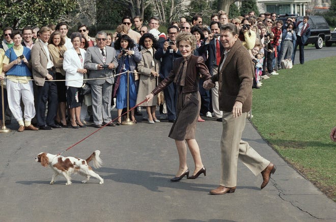 President Ronald Reagan, right, and First Lady Nancy Reagan, center, walk with their dog Rex on the South Lawn of the White House after they returned by helicopter from Camp David, Md. where the first family has spent the weekend, March 16, 1986, Washington, D.C.
