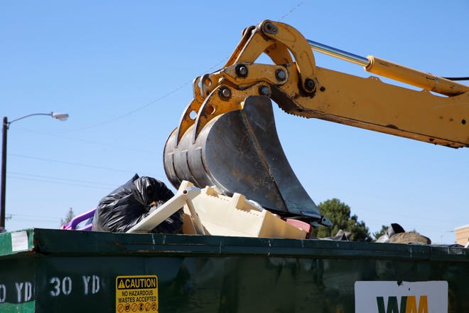 Large household trash is crushed by a backhoe during the City of Farmington's Spring Dumpster Weekend on April 10 at Berg Park in Farmington.