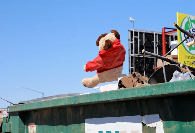 A stuffed toy flies into a dumpster during the City of Farmington's Spring Dumpster Weekend on April 10 at Berg Park in Farmington.