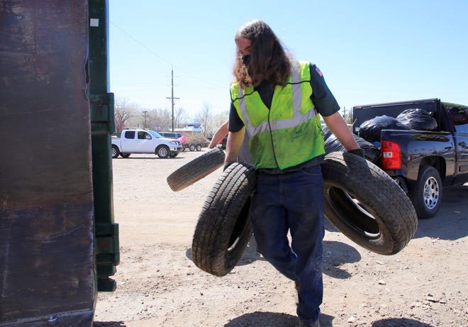 An employee with Waste Management helps a Farmington resident unload tires at the city's Spring Dumpster Weekend on April 10 at Berg Park in Farmington.